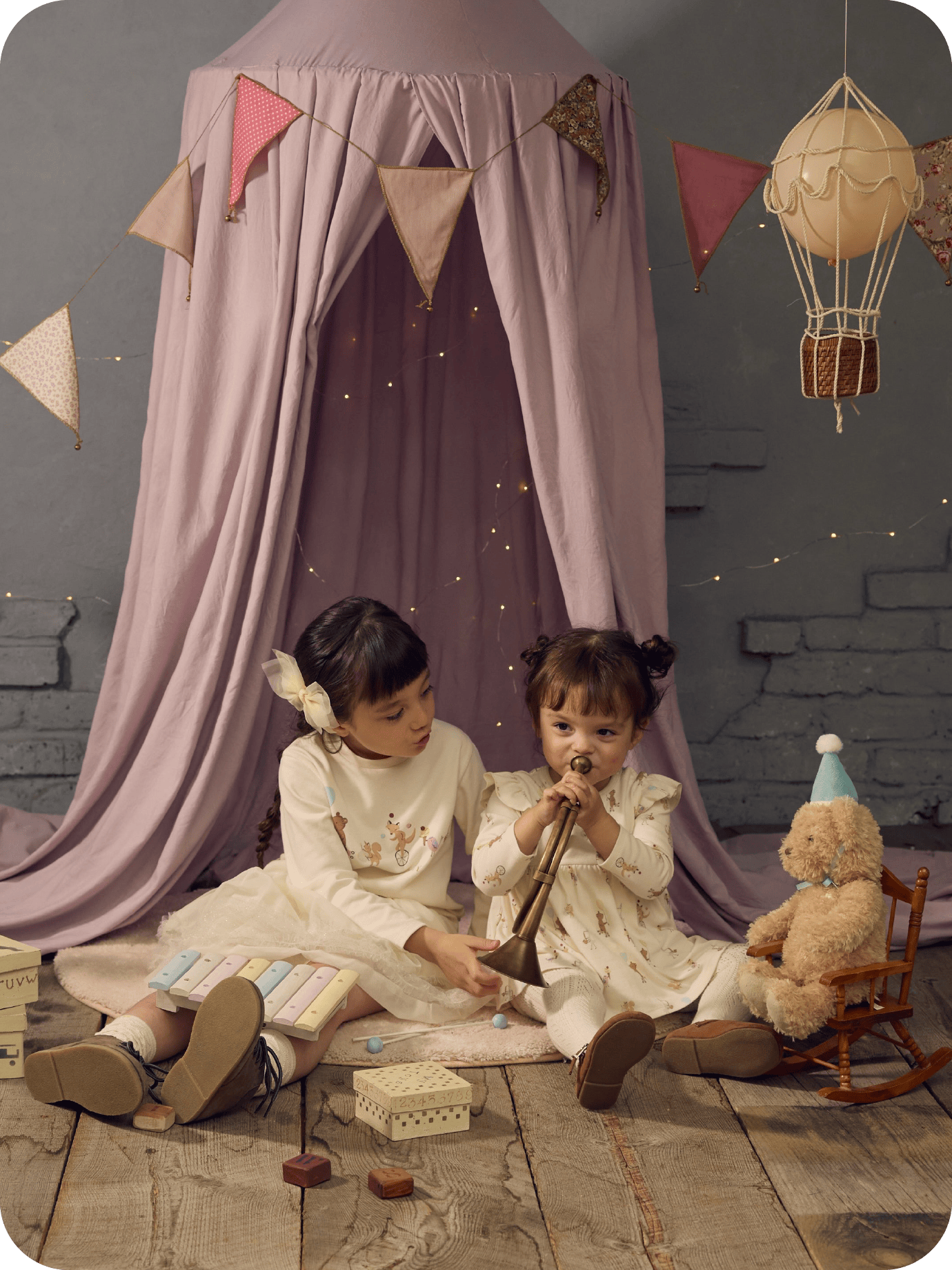 布地のテントの下で2人の女の子が座っている画像