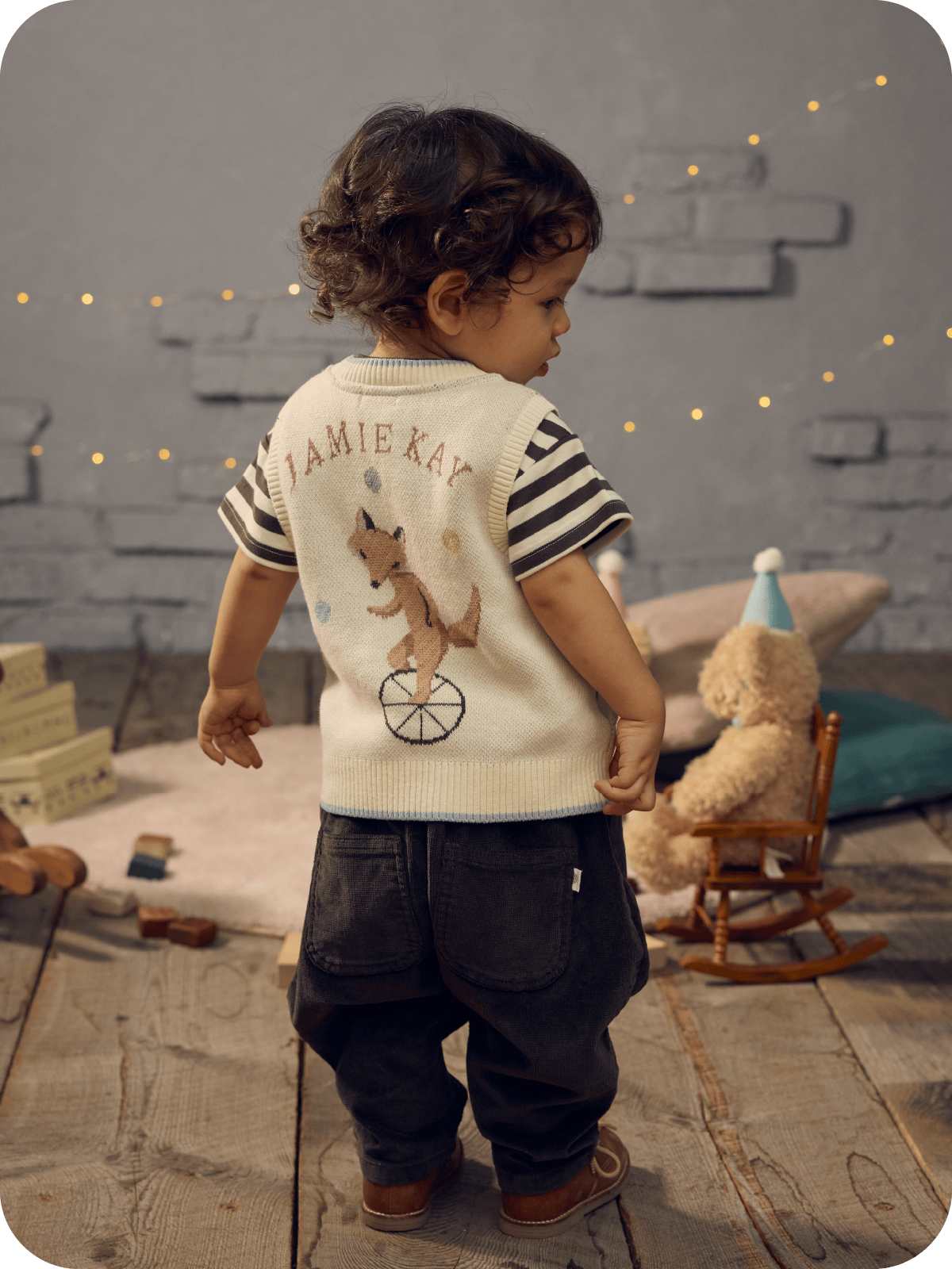 一輪車に乗ったキツネのバックプリントが入った服を着た男の子が立っている画像