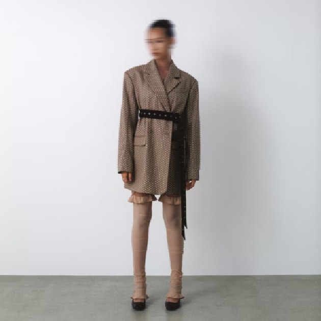 キャメルのコートにロングブーツを着た女性が立っているの画像