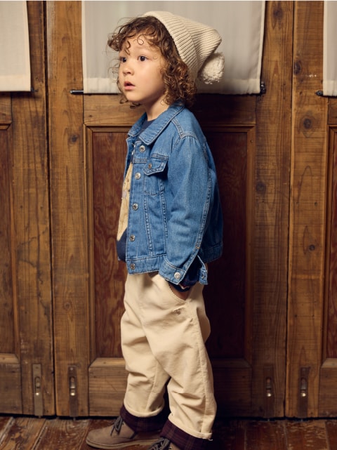 ジージャンにベージュのパンツを着た子供が斜め左上を向いている画像